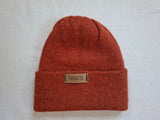 Orange wool knit beanie with a visible brand label on a light gray background