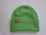 Green knit beanie with a brown leather patch on a light gray background