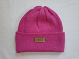 Pink knit beanie with a brand label on a light gray background