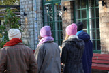 Four people wearing different colored beanies standing outside a building with stone walls.
