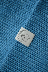 White organic cotton logo of a cute alpaca featuring the brand 'YANANTIN' on a blue woolen hat