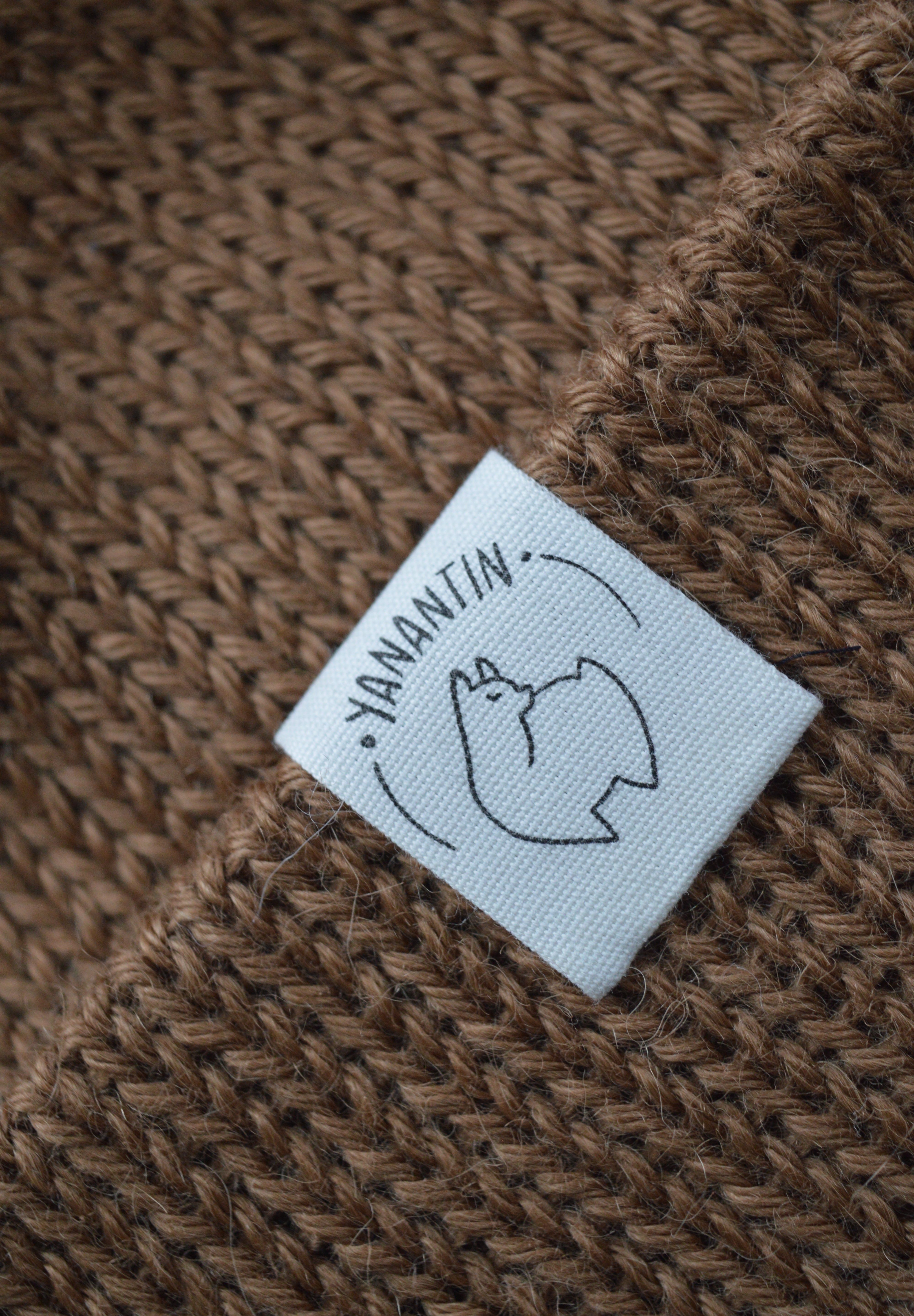 Close-up of a label on a brown knitted fabric, featuring the brand 'YANANTIN'.
