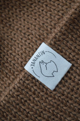 Close-up of a label on a brown knitted fabric, featuring the brand 'YANANTIN'.