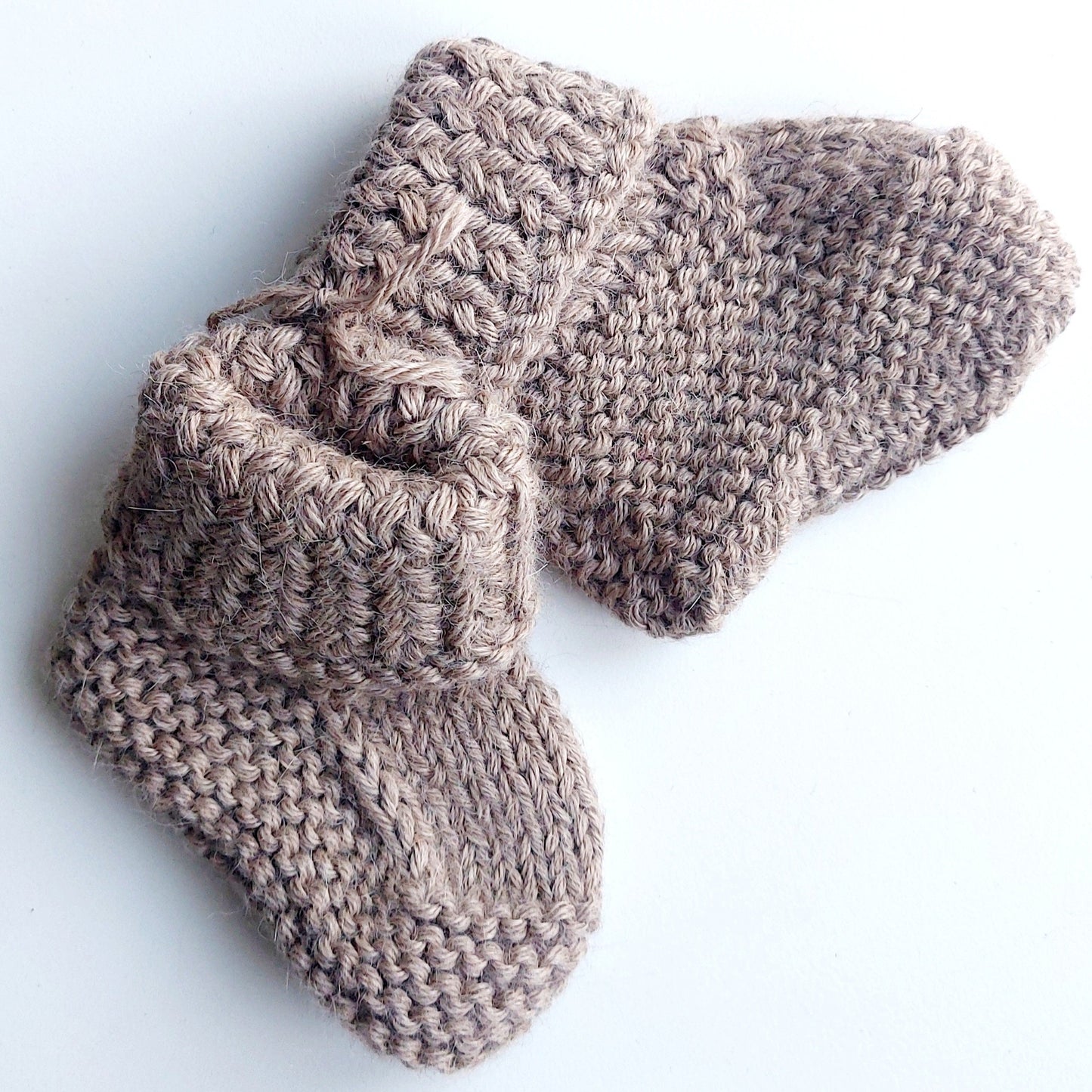 Handmade knitted baby socks in light brown with folded ankle cuffs, made from 100% baby alpaca wool—soft, stretchy, and perfect for little feet.