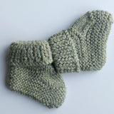 Handmade knitted baby socks in light green with folded ankle cuffs, made from 100% baby alpaca wool—soft, stretchy, and perfect for little feet.
