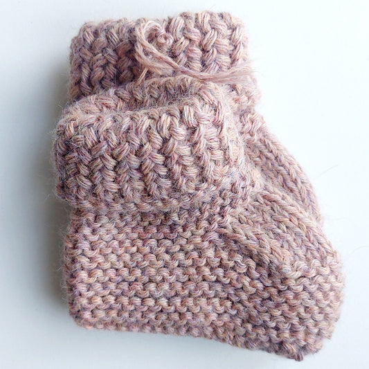 Handmade knitted baby socks in light pink with folded ankle cuffs, made from 100% baby alpaca wool—soft, stretchy, and perfect for little feet.

