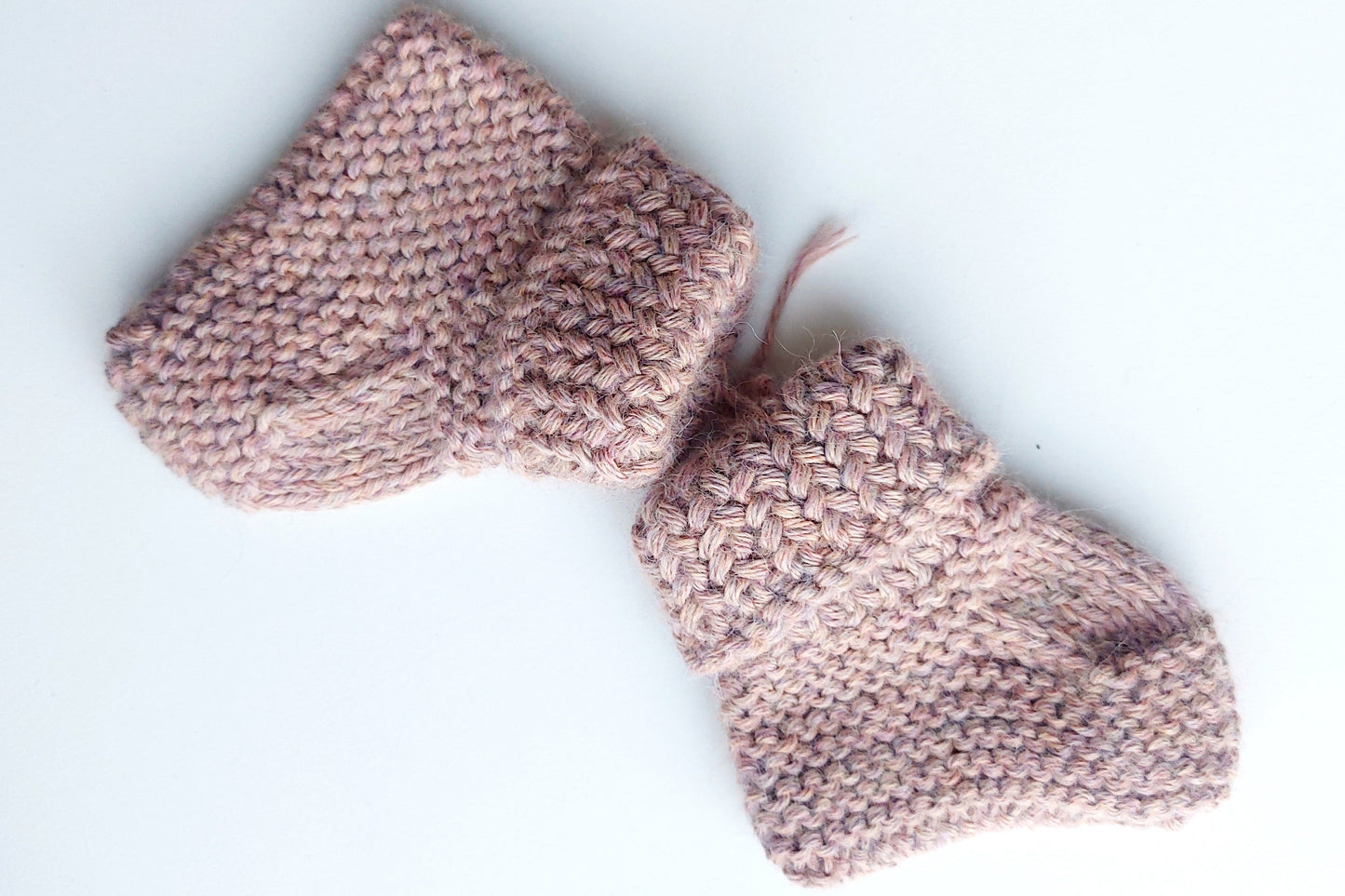 Handmade knitted baby socks in light pink with folded ankle cuffs, made from 100% baby alpaca wool—soft, stretchy, and perfect for little feet.