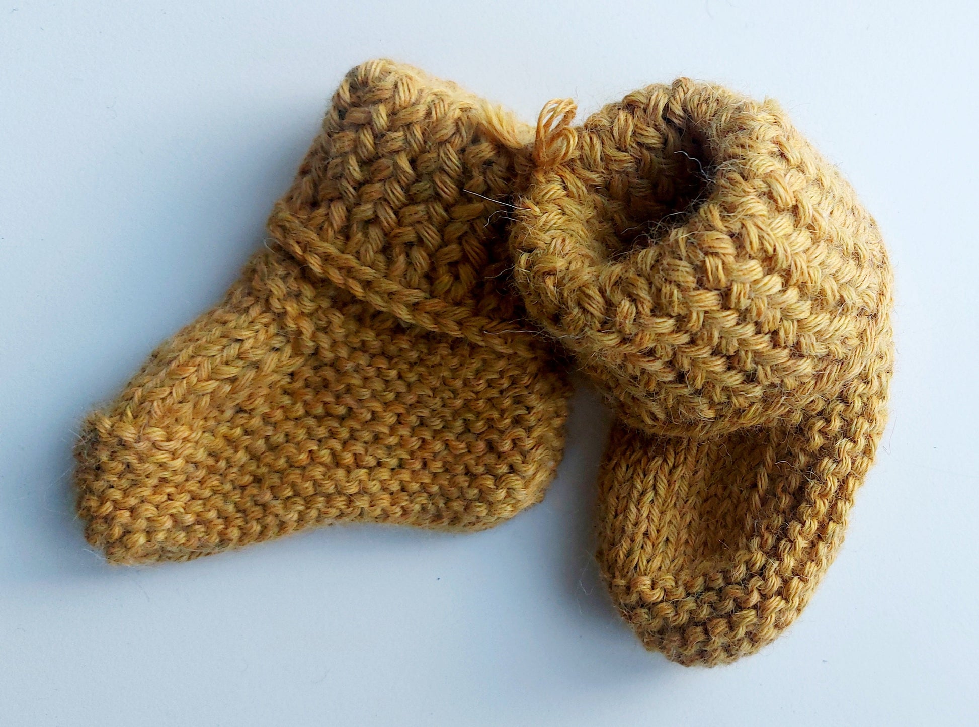 Handmade knitted baby socks in ochre yellow with folded ankle cuffs, made from 100% baby alpaca wool, soft and stretchy.