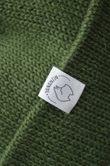 White organic cotton logo of a cute alpaca featuring the brand 'YANANTIN' on a green woolen hat