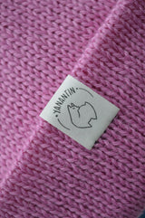 White organic cotton logo of a cute alpaca featuring the brand 'YANANTIN' on a pink woolen hat