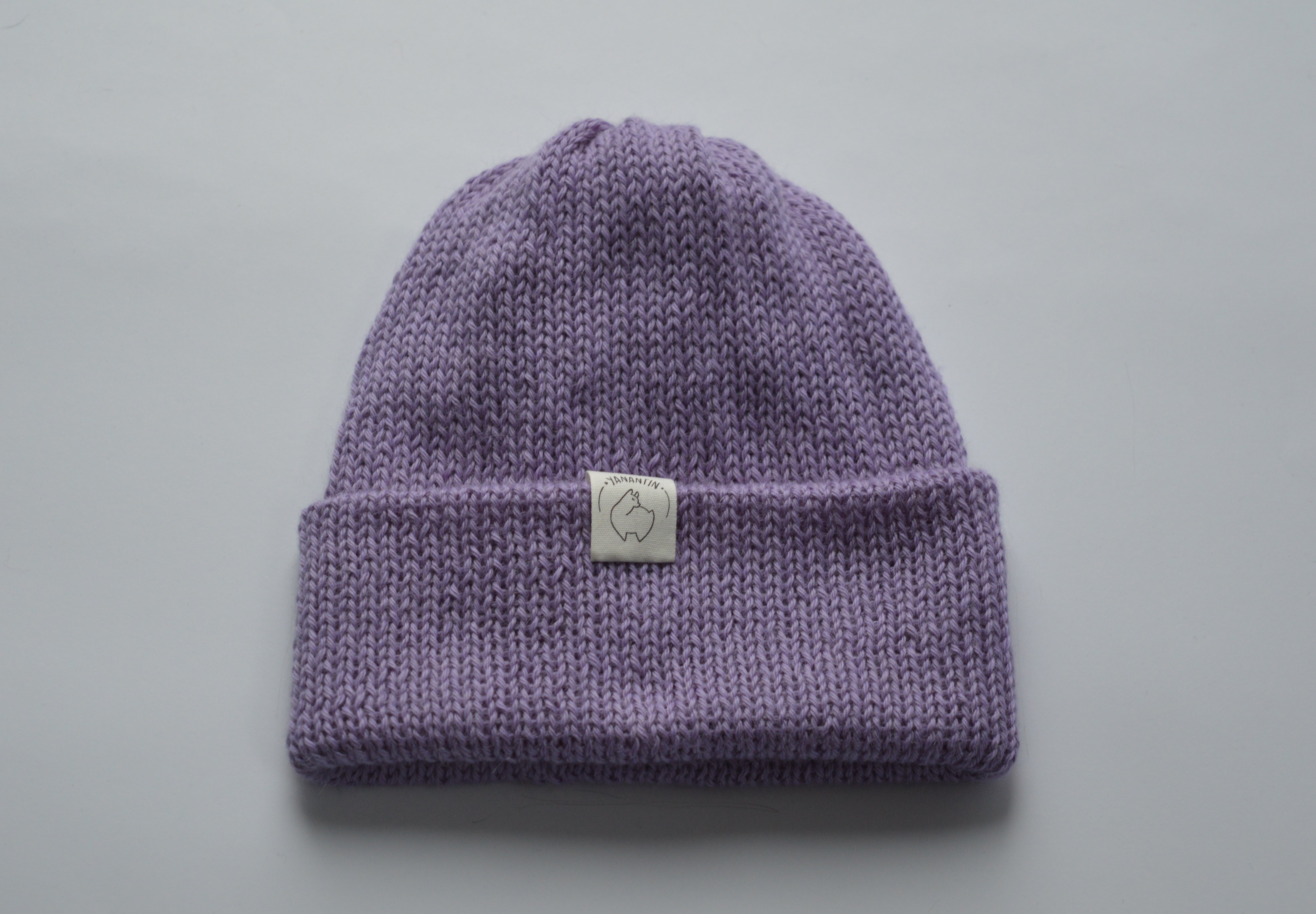 Lavender purple knitted baby alpaca hat with a white organic cotton label and folded brim