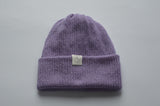 Lavender purple knitted baby alpaca hat with a white organic cotton label and folded brim