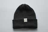 Dark gray baby alpaca knit beanie with a white organic cotton label and a folded brim
