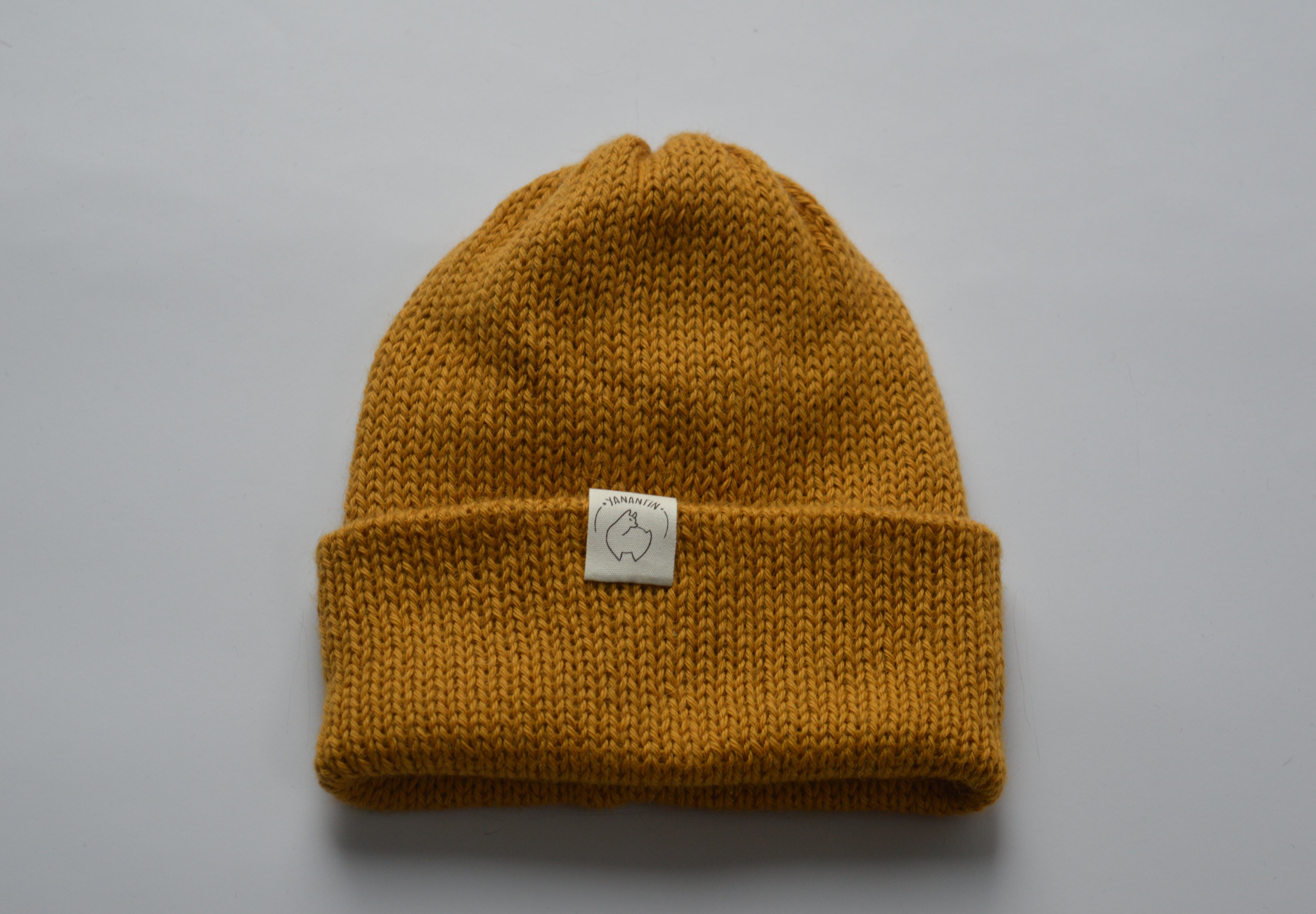 Yellow knitted baby alpaca hat with a white organic cotton label and folded brim