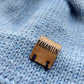 Close-up of the brown vegan leather label on the handmade light blue baby hat, highlighting its quality and style.