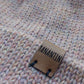 Close-up of the brown vegan leather label on the handmade light pink baby hat.