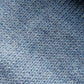Close-up of the soft knitted texture of the handmade light blue baby hat, made from 100% baby alpaca wool with a foldable edge and pompom.