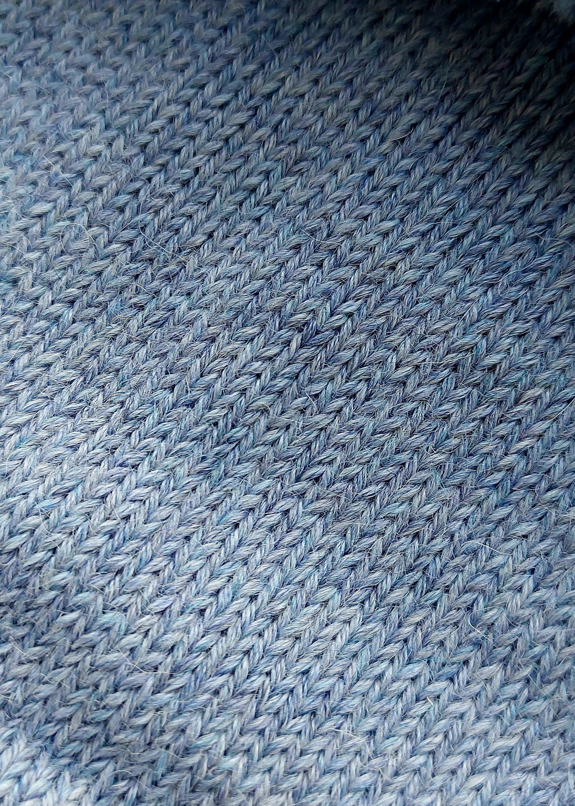Close-up of the soft knitted texture of the handmade light blue baby hat, made from 100% baby alpaca wool with a foldable edge and pompom.