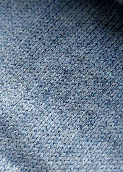 Close-up of the soft knitted texture of the handmade light blue baby hat, made from 100% baby alpaca wool with a foldable edge and pompom.