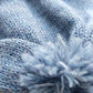 Close-up of the pompom on the handmade light blue baby hat, made from soft 100% baby alpaca wool with a foldable edge and brown vegan leather label.