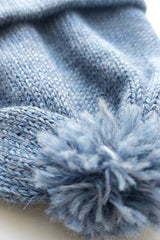 Close-up of the pompom on the handmade light blue baby hat, made from soft 100% baby alpaca wool with a foldable edge and brown vegan leather label.