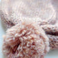 Close-up of the pompom on the handmade light pink baby hat, made from soft 100% baby alpaca wool with a foldable edge and brown vegan leather label.