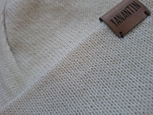 Close-up of a beige knitted wool fabric with a 'YANANTIN' label on a textured background