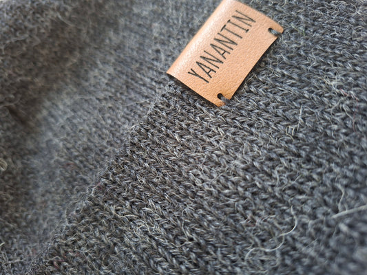 Close-up of a textured gray knitted woolen hat with a 'YANANTIN' label.
