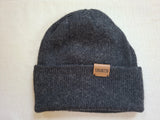 Gray knit beanie with a brown leather patch on a light beige background