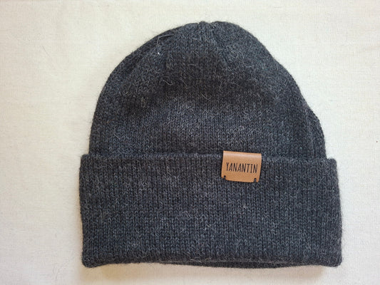 Gray knit beanie with a brown leather patch on a light beige background