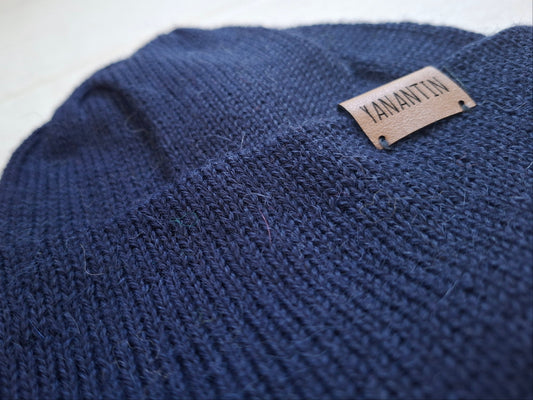 Navy blue knitted wool hat with a brand label on a white background